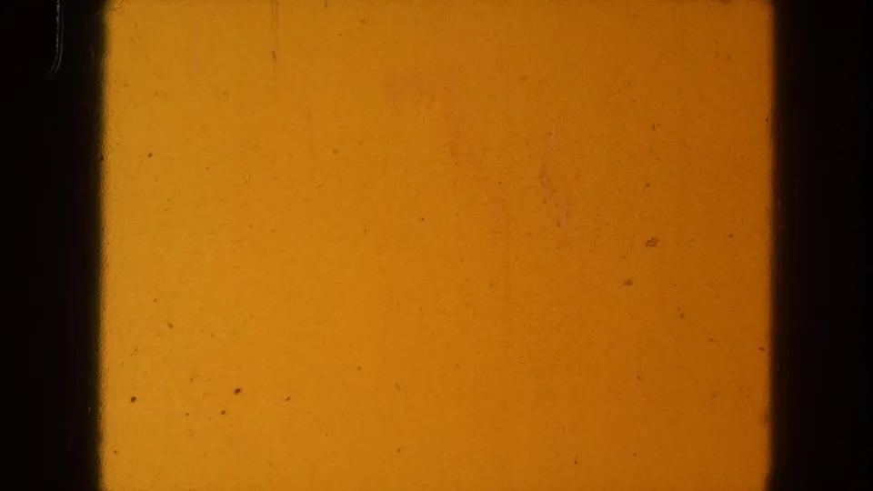 1954 8mm source frame with orange-yellow exposure, a broad black vertical divider, dark side edge, and visible dust specks.