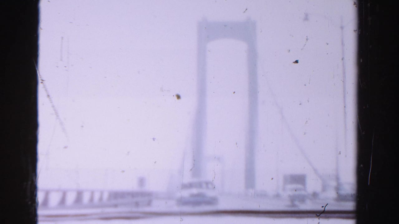 Suspension bridge tower and roadway seen through haze from a vehicle.