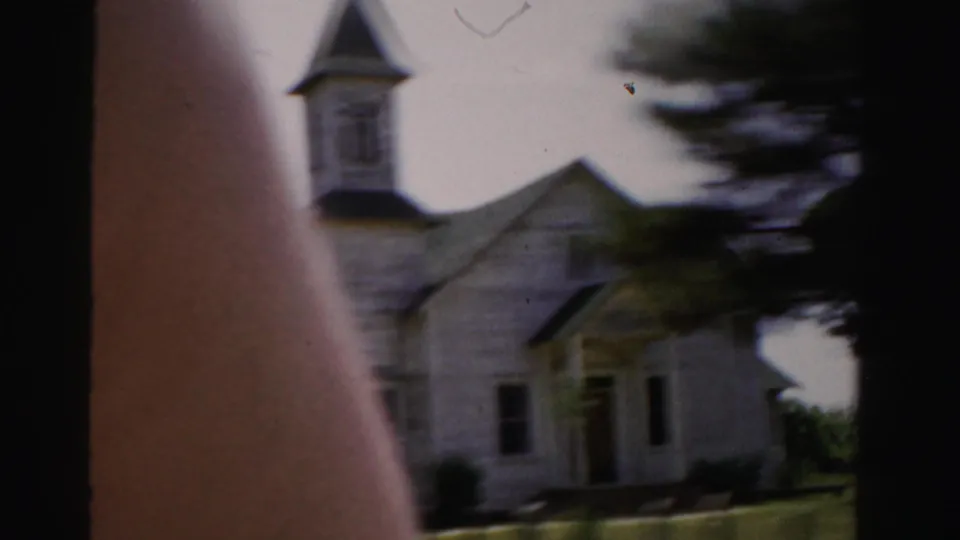 1955 Dade County view of a small white church-like building with a steeple, trees, and car-window framing.