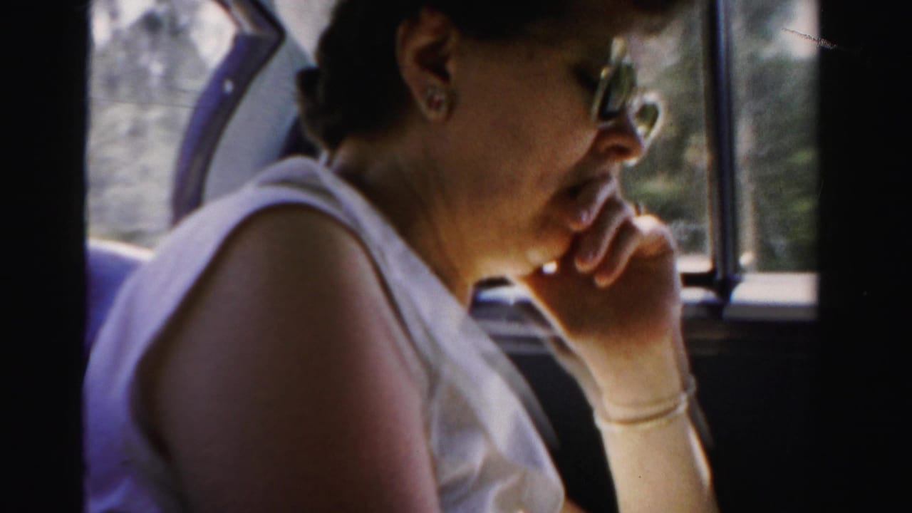 A woman in sunglasses and a white sleeveless top sits by a vehicle window during a 1955 Dade County, Florida road trip.