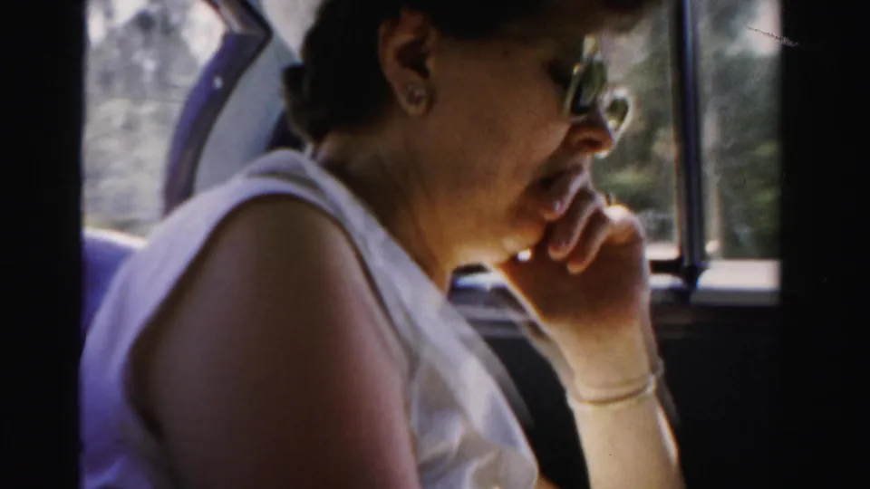 A woman in sunglasses and a white sleeveless top sits by a vehicle window during a 1955 Dade County, Florida road trip.