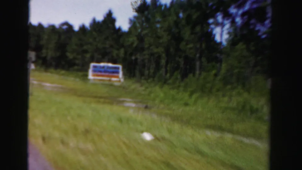 The car passes a large roadside sign set against grass and pine trees in Dade County, Florida, in 1955 footage.