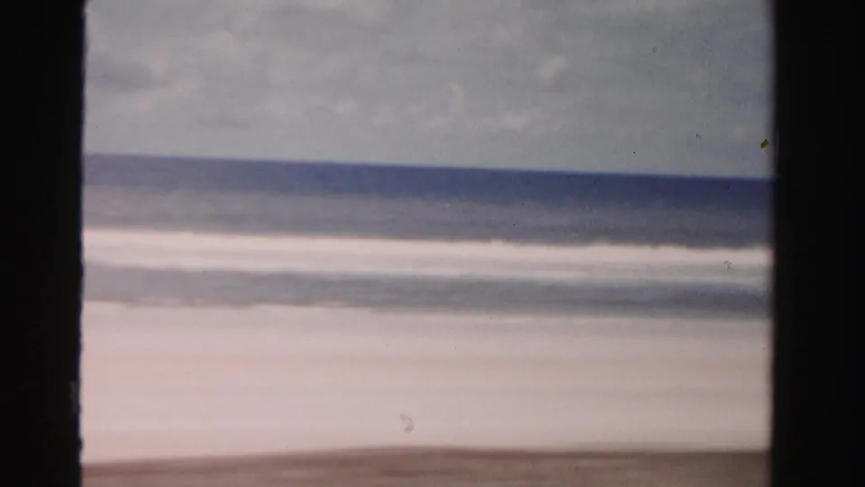 1955 Dade County, Florida beach view from a moving car, with surf, horizon, and dark window-like borders.