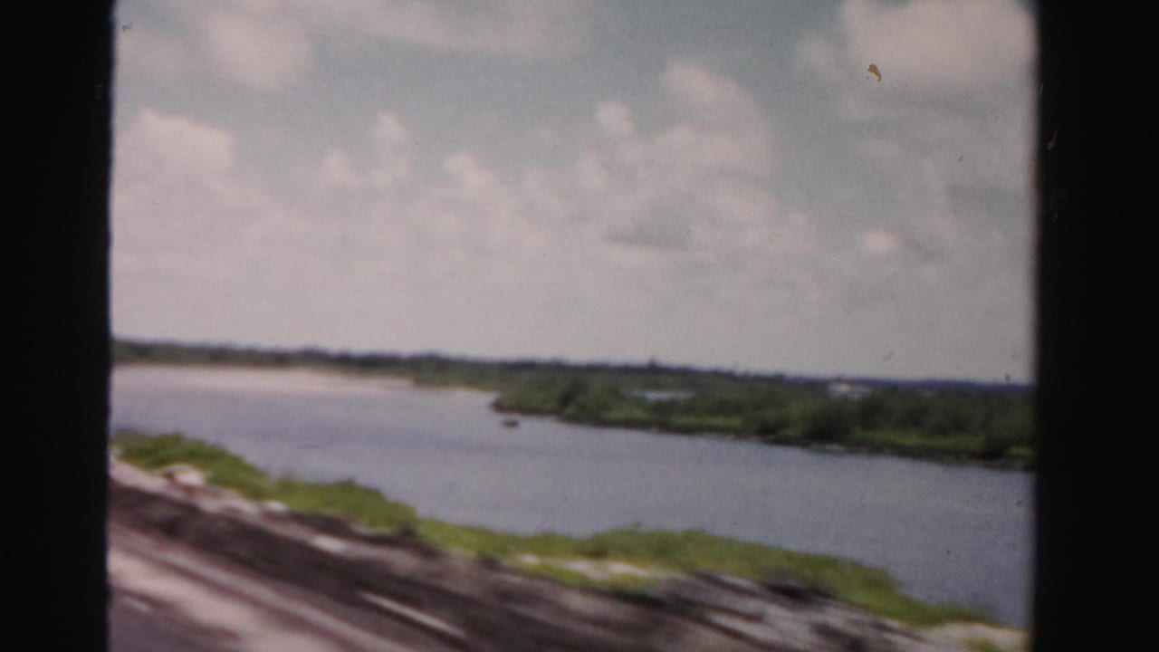 Wide waterway curving past low green banks under a cloudy sky.