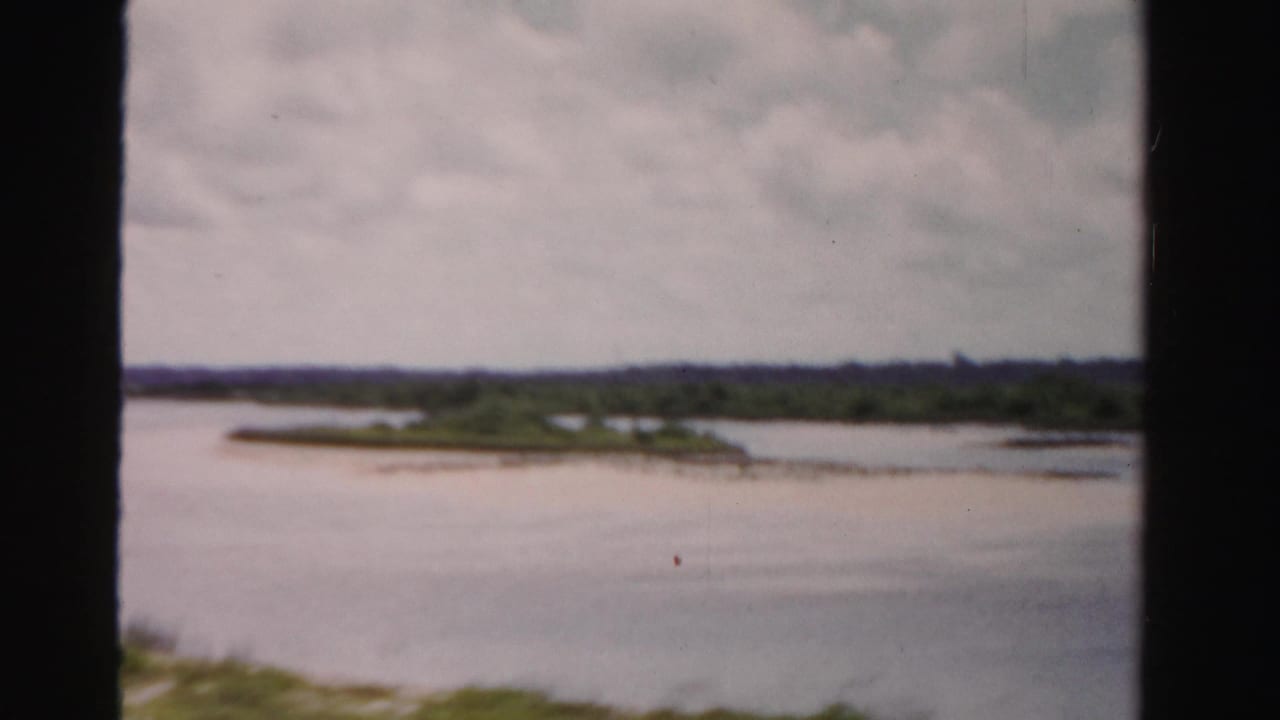 Wide waterfront view with distant greenery and dark film-strip borders.