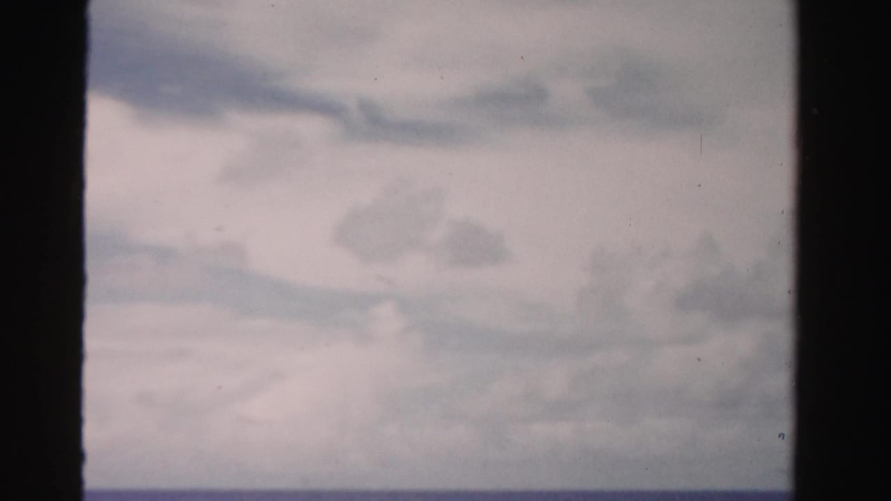 Soft cloudy sky and pale horizon framed by dark film borders.