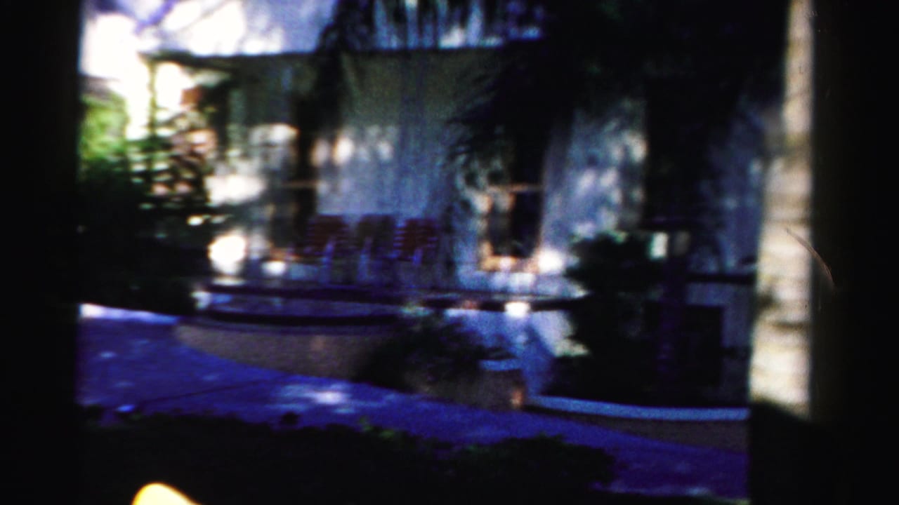 Sunlit white building with porch or patio area seen through heavy shadow.