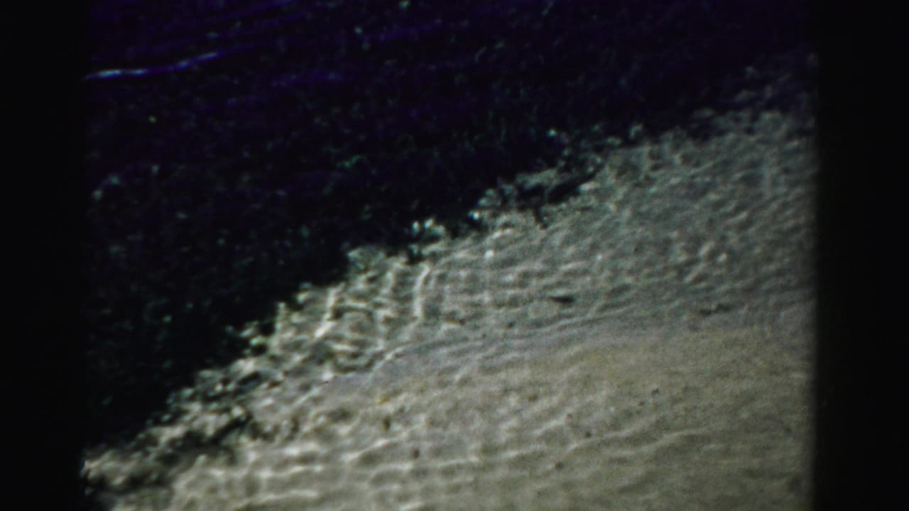 Shallow water moving over rippled sand with dark water above.