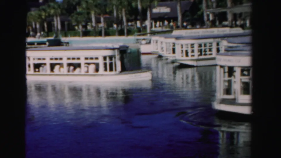 Clustered white passenger boats appear along a 1955 Dade County waterfront, with dark water and a palm-lined background.