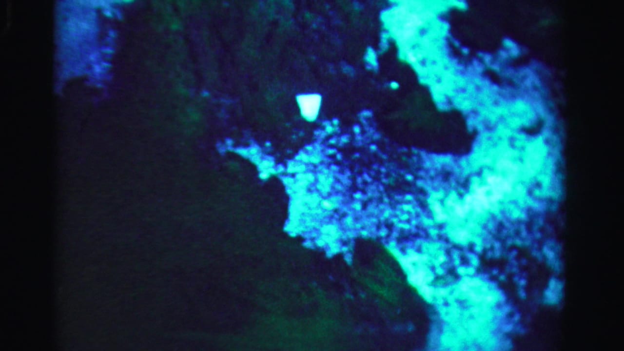 Bright blue-green reflection cluster against a dark background with soft edges.