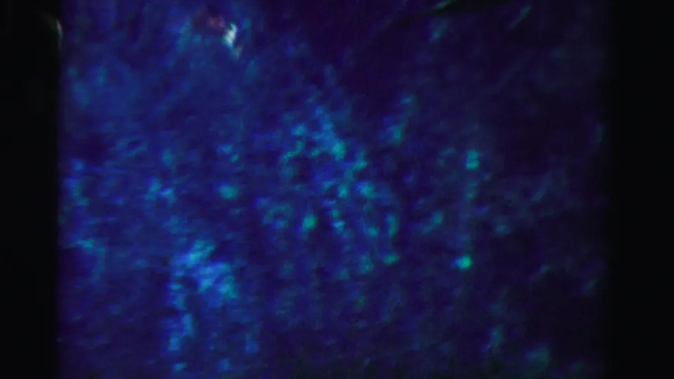 1955 Dade County 8mm frame showing a darker blue underwater surface with mottled light and minimal distinct detail.