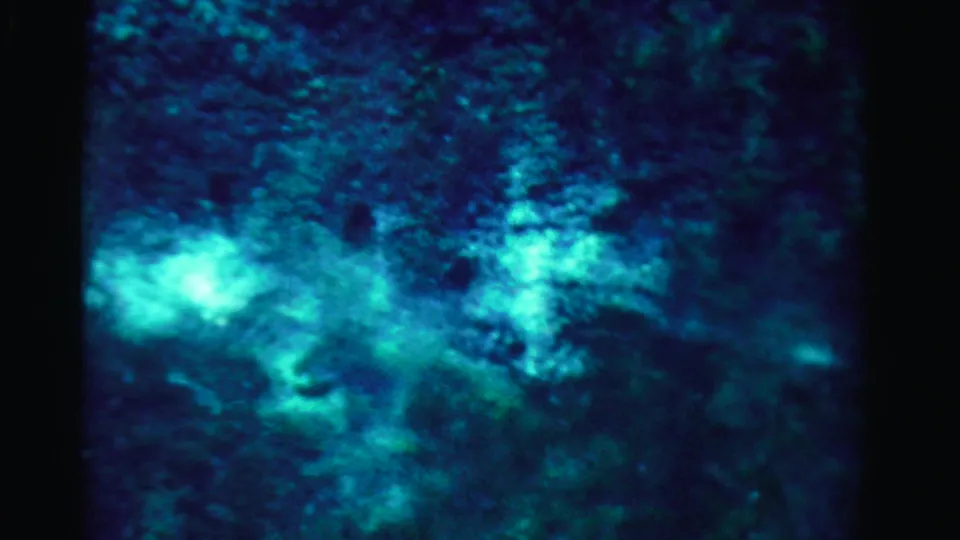 1955 Dade County 8mm frame showing blue-green underwater texture with a bright reflection near the lower edge.
