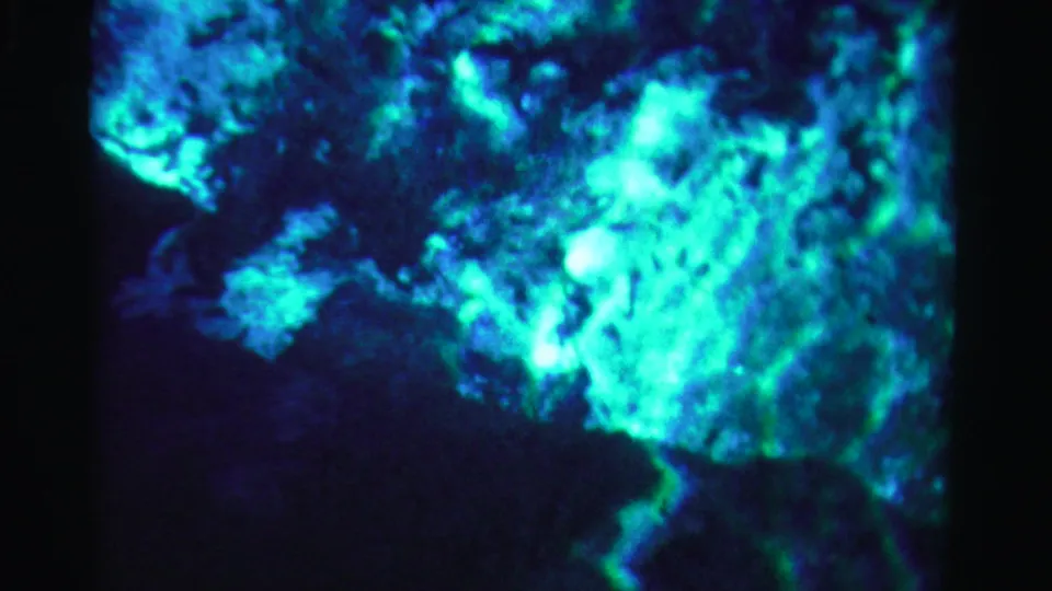 1955 Dade County 8mm frame with vivid turquoise mottling over a dark blue water-like background.