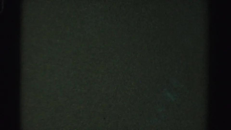1955 Dade County 8mm frame showing very dark underwater texture with faint green-blue light and visible film border.
