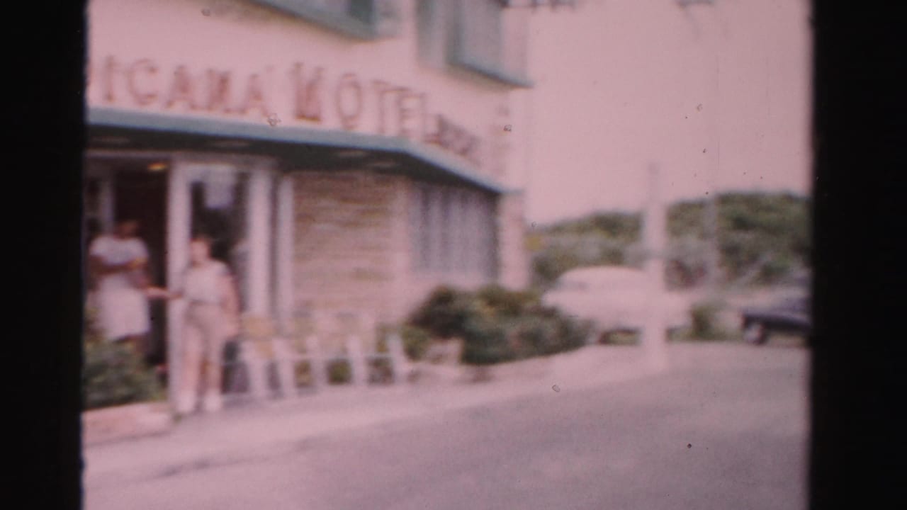 1955 Dade County motel frontage showing two adults at the entrance under Tropicana Motel signage and parked cars beyond.