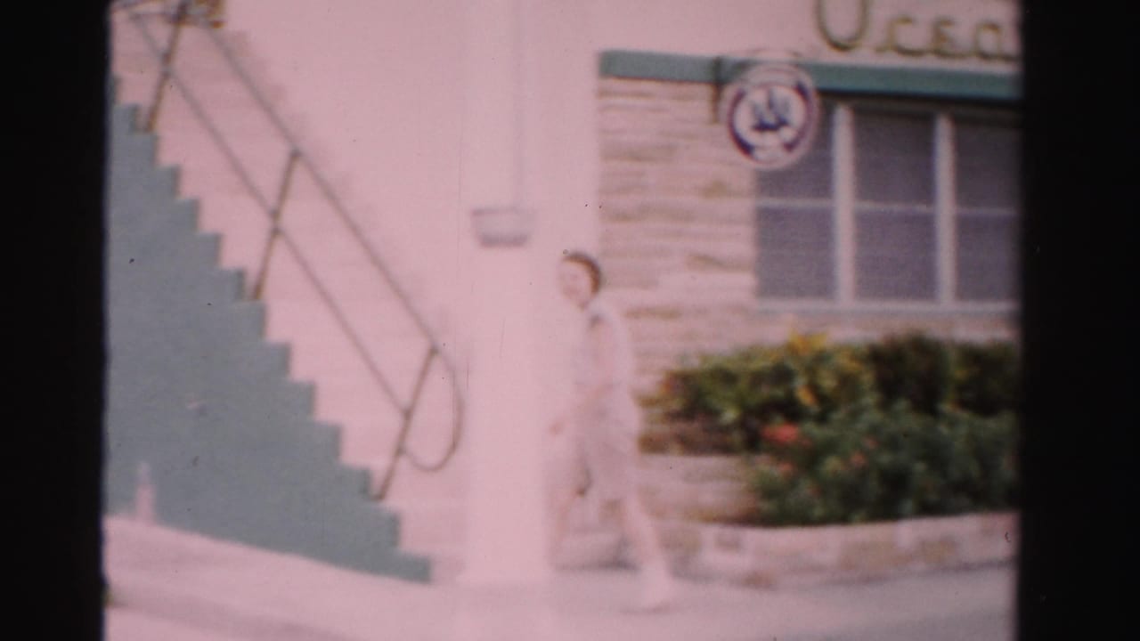 The woman continues along the sidewalk beside exterior stairs at the Ocean Tropicana Motel in Dade County, Florida.