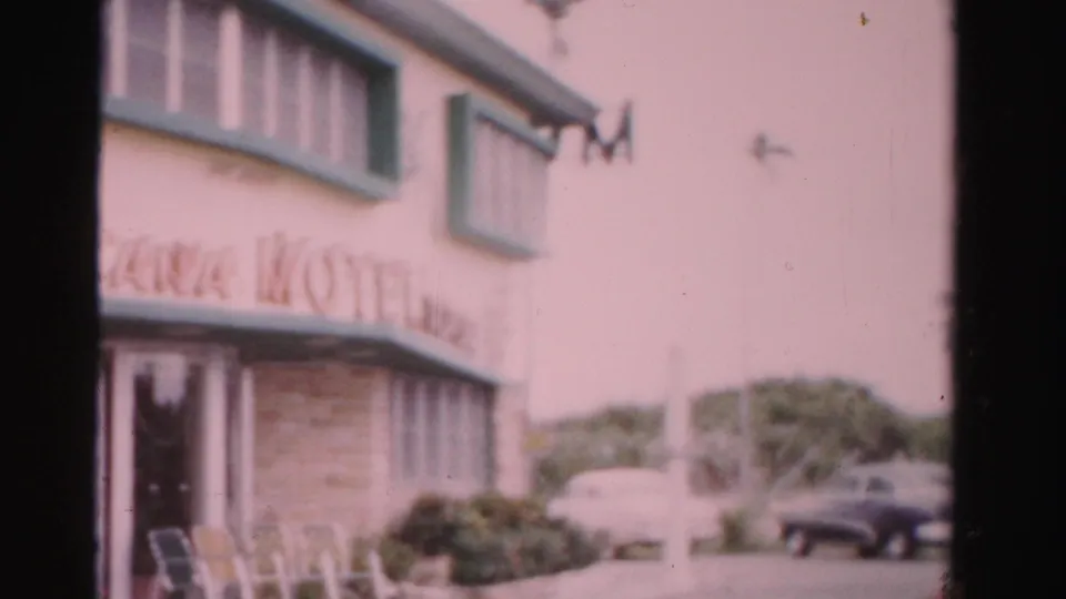 A soft 8mm view shows the motel corner, partial Ocean Tropicana signage, front windows, and mid-century cars near the property.