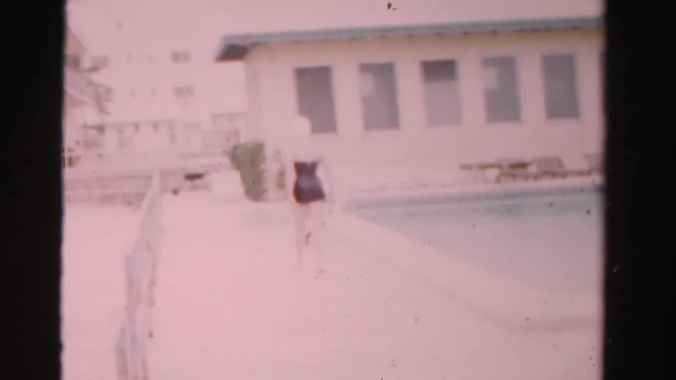 A soft 8mm frame shows the swimsuit-clad woman farther down the bright poolside patio in Dade County, Florida.