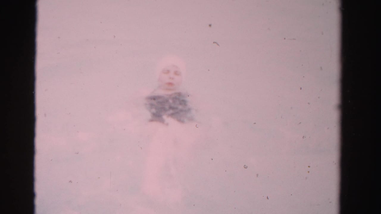 Woman in a pool seen through faded 8mm film with heavy grain and scratches.