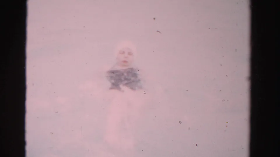In 1955 Dade County home-movie footage, a woman in a dark swimsuit and light head covering swims through pale pink-tinted water.