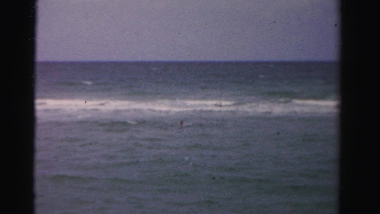 Distant ocean waves seen through a dark vertical frame.
