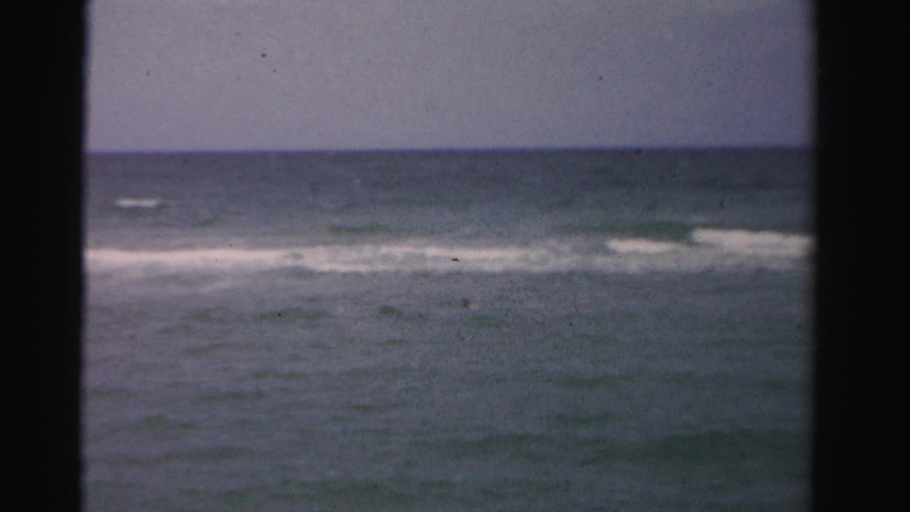 Small surf line and open water framed by dark vertical edges.