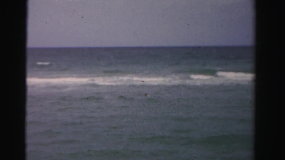Faded 8mm coastal view in Dade County, Florida, showing small waves breaking offshore with no clear faces visible.
