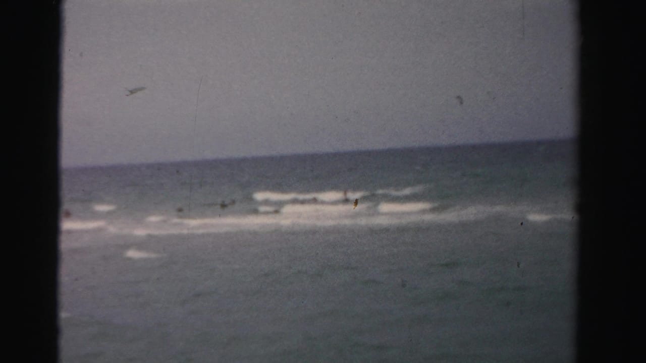 Distant swimmer in the ocean with small waves and a pale horizon.