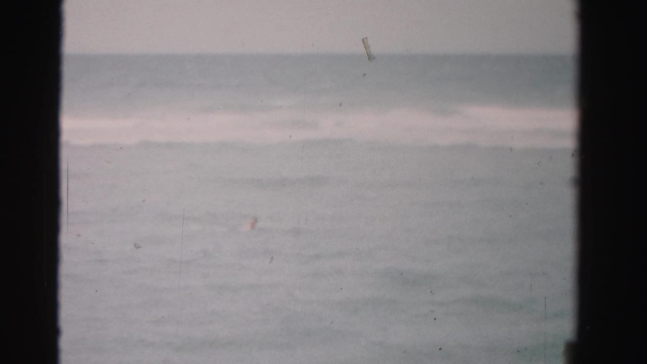 Distant ocean horizon with soft waves and dark 8mm film edges.