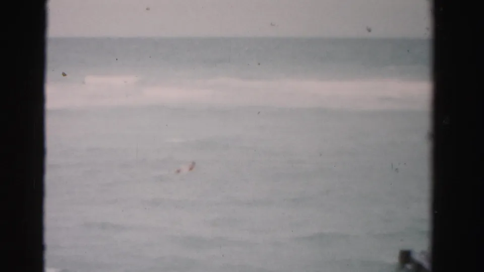 Faded 8mm frame of Dade County ocean water with a low horizon, rolling waves, and visible gate edges.