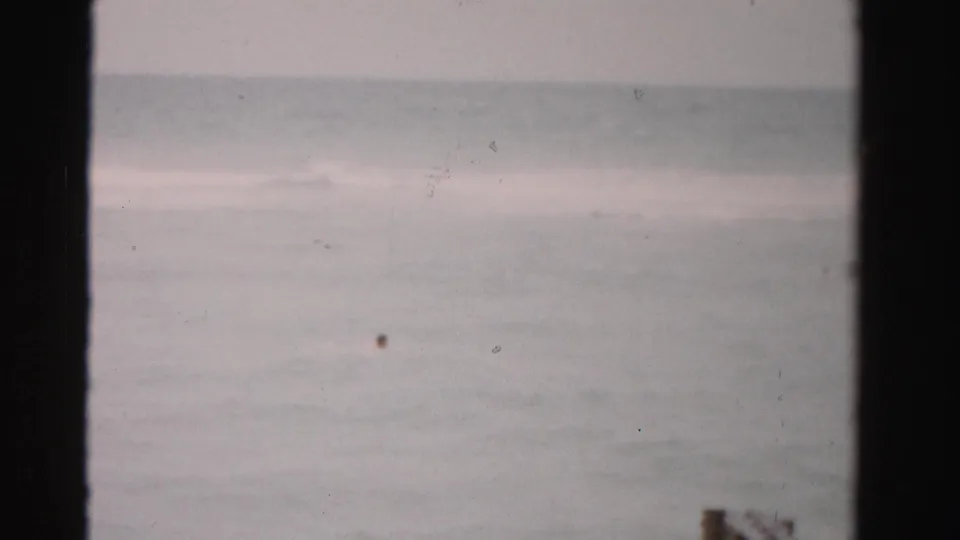 Dade County 1955 ocean scene with a tiny distant swimmer near the lower right and soft waves beyond.