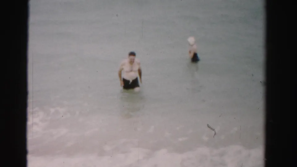 1955 Dade County beach frame with the man closer to camera and the woman farther out in the muted ocean water.