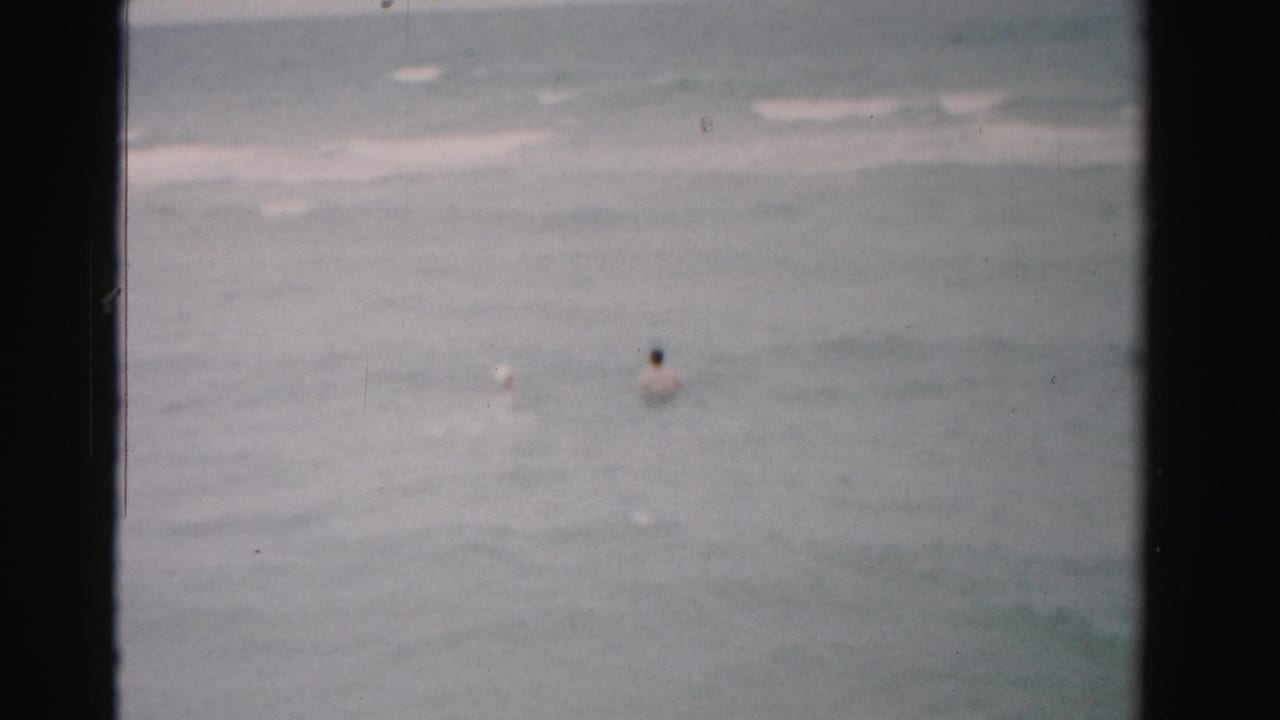 Distant bathers floating in gray-blue ocean water.