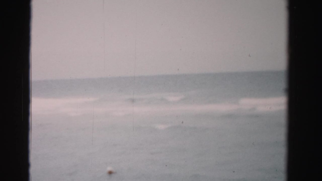Distant surf and horizon seen through dark 8mm film borders.