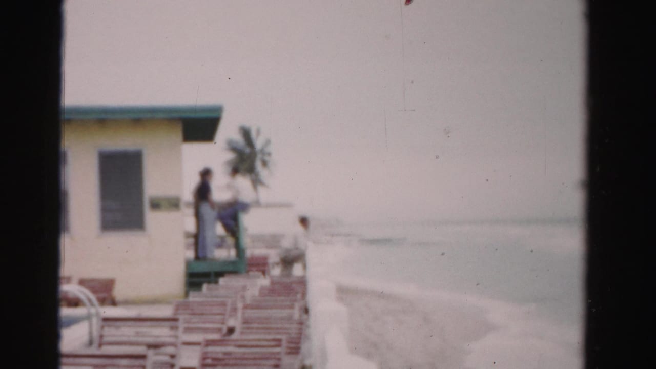 Lifeguard station and beach chairs beside the ocean with several people visible.