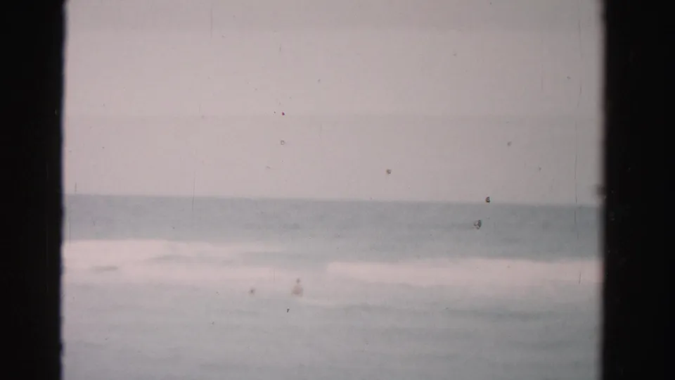 1955 Dade County beach footage shows a soft ocean horizon and pale surf within visible 8mm frame borders.