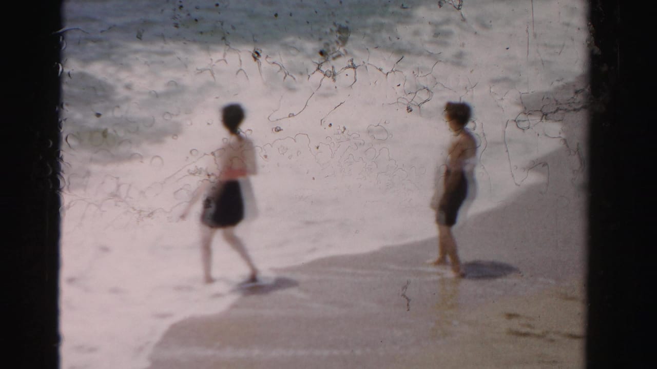 In 1955 Dade County beach footage, two women in swimsuits appear near the shoreline as waves break behind them.