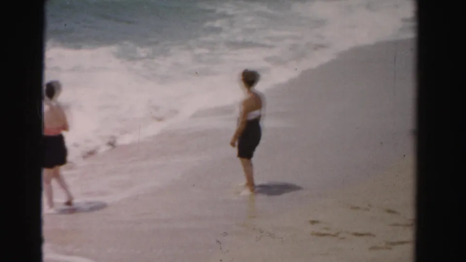 1955 Dade County beach footage shows two women near the surf, with one partly cropped by the 8mm frame edge.