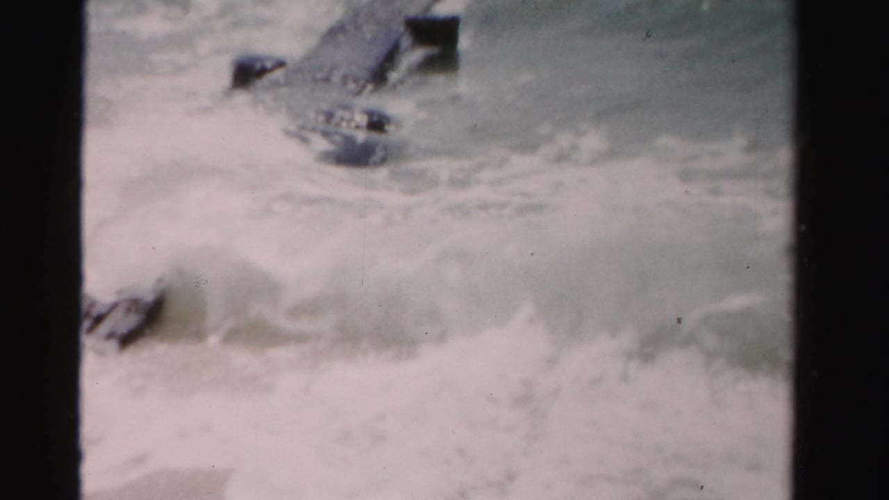 Rough ocean water surges around dark wooden deck elements.