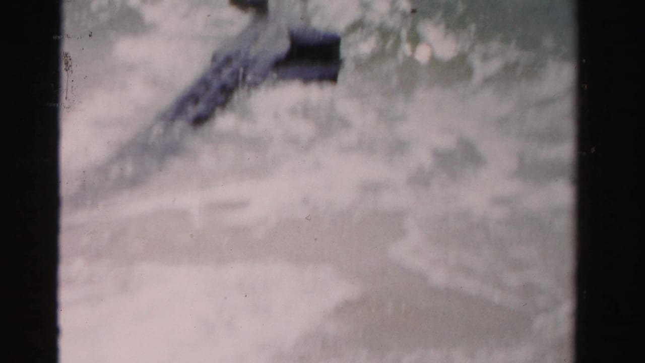 White surf washes over a slanted wooden deck or walkway.