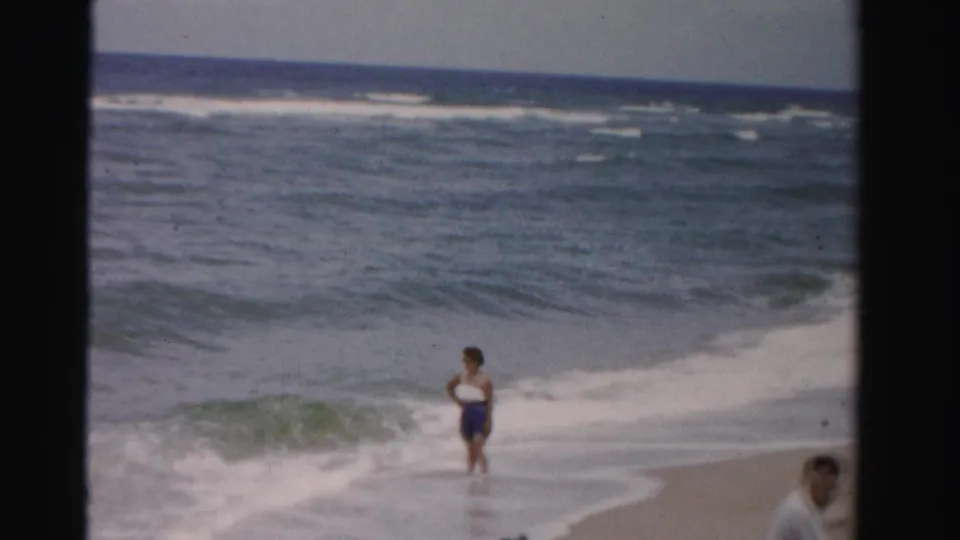 Wider 1955 Dade County beach view showing surf, sand, and a person near the waterline.