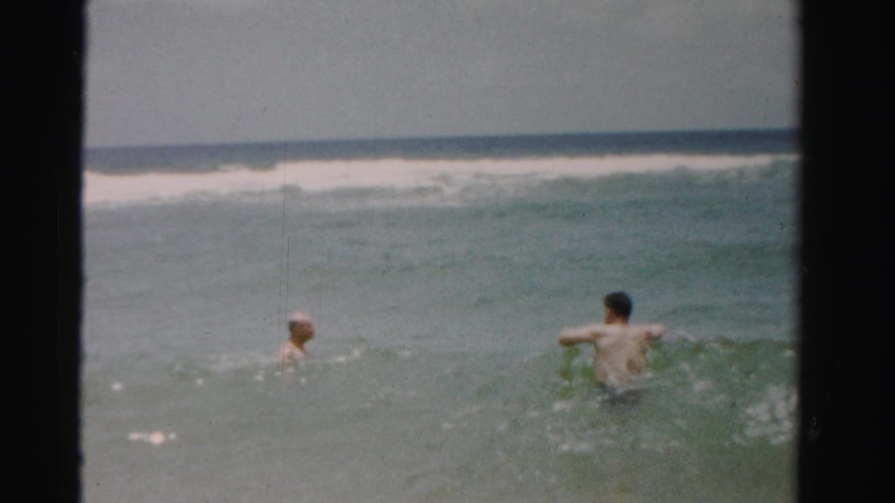 Two adult men wade waist-deep in the ocean in supplied 1955 Dade County, Florida 8mm home-movie footage.