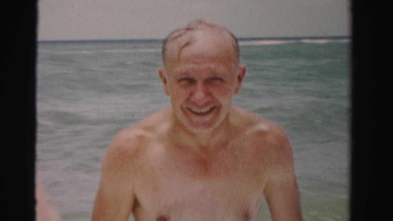 Smiling elderly man close to the camera in choppy ocean water.