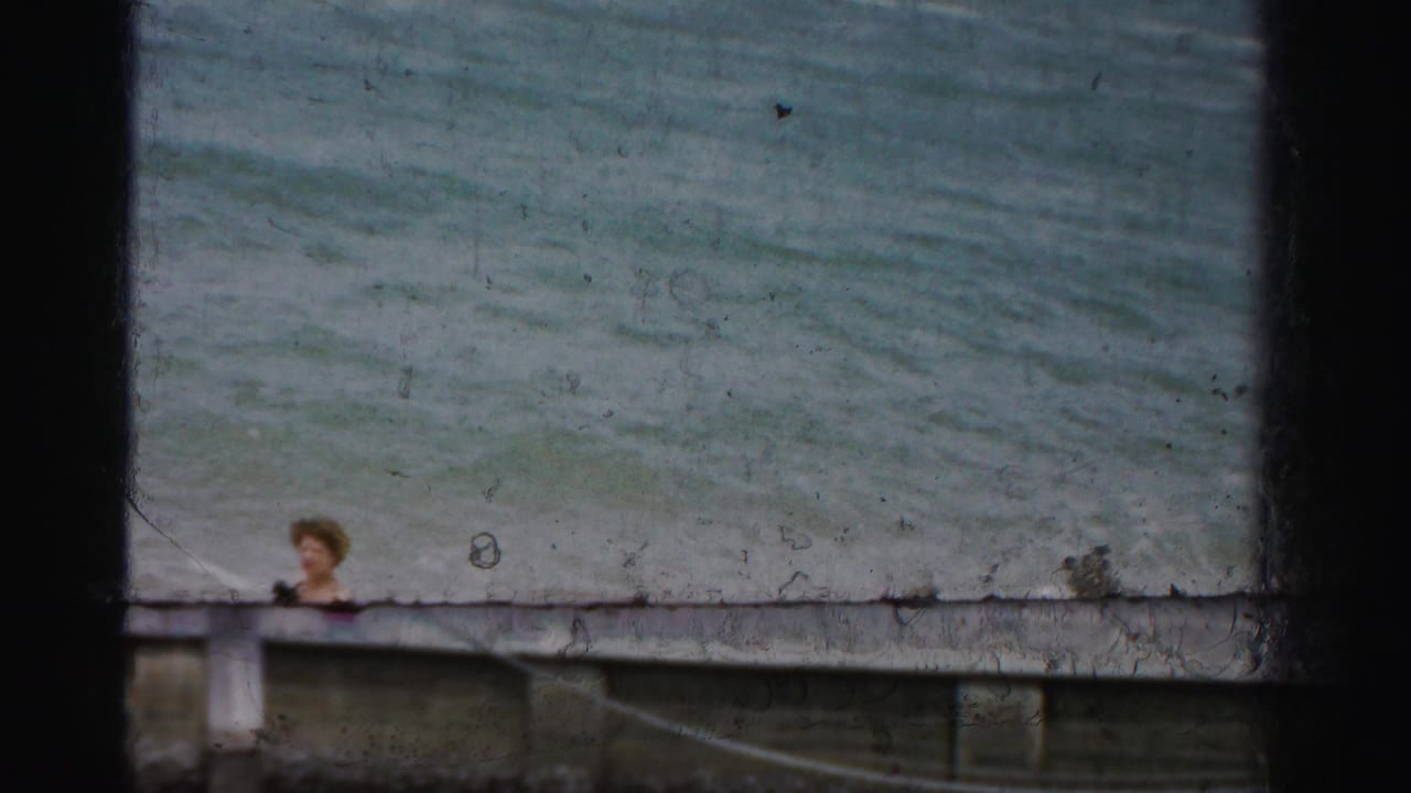 Person partly visible behind a waterfront railing with ocean water beyond.