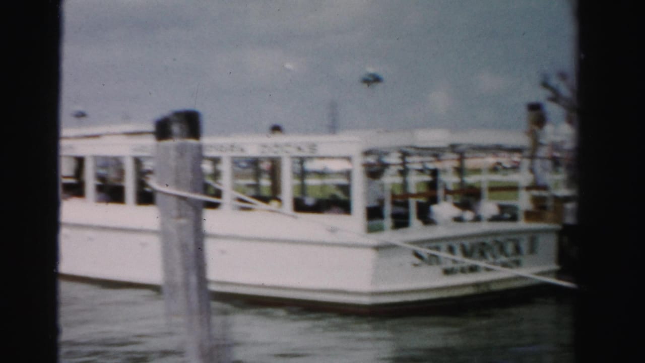 White ferry beside wooden pilings at a Miami Beach dock with passengers visible onboard.