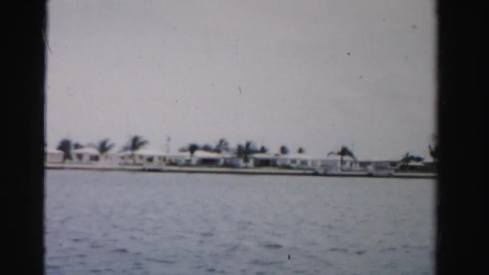 Dade County waterfront scene on 8mm film, with white homes and palms across the water.