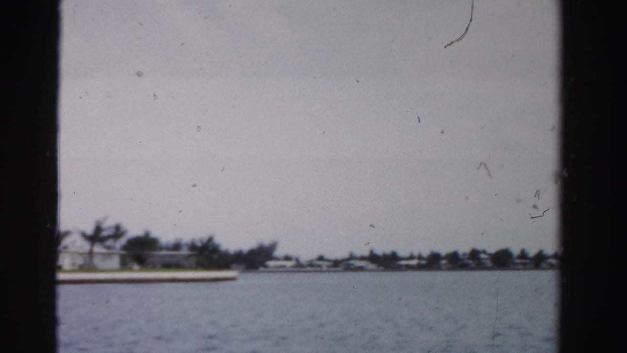 Waterway seen through dark 8mm frame borders with a low distant shoreline and small houses.