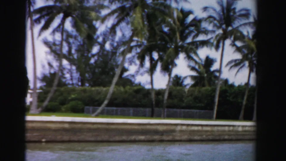 The final frame shows canal water and a landscaped Dade County shoreline with palms, hedges, lawn, and the landing now mostly out of view.