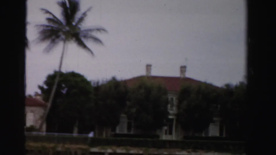 The final 1955 Dade County frame shows a red-roofed residence partly obscured by dark trees, palms, hedges, and cloudy sky.