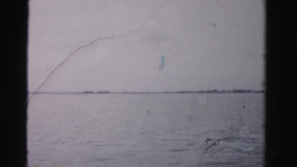 1955 Dade County home-movie frame showing open waterfront under a muted sky before the shoreline building appears.
